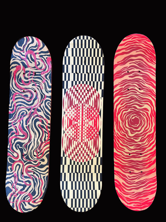 Three skateboard decks with unique patterns on a wooden surface