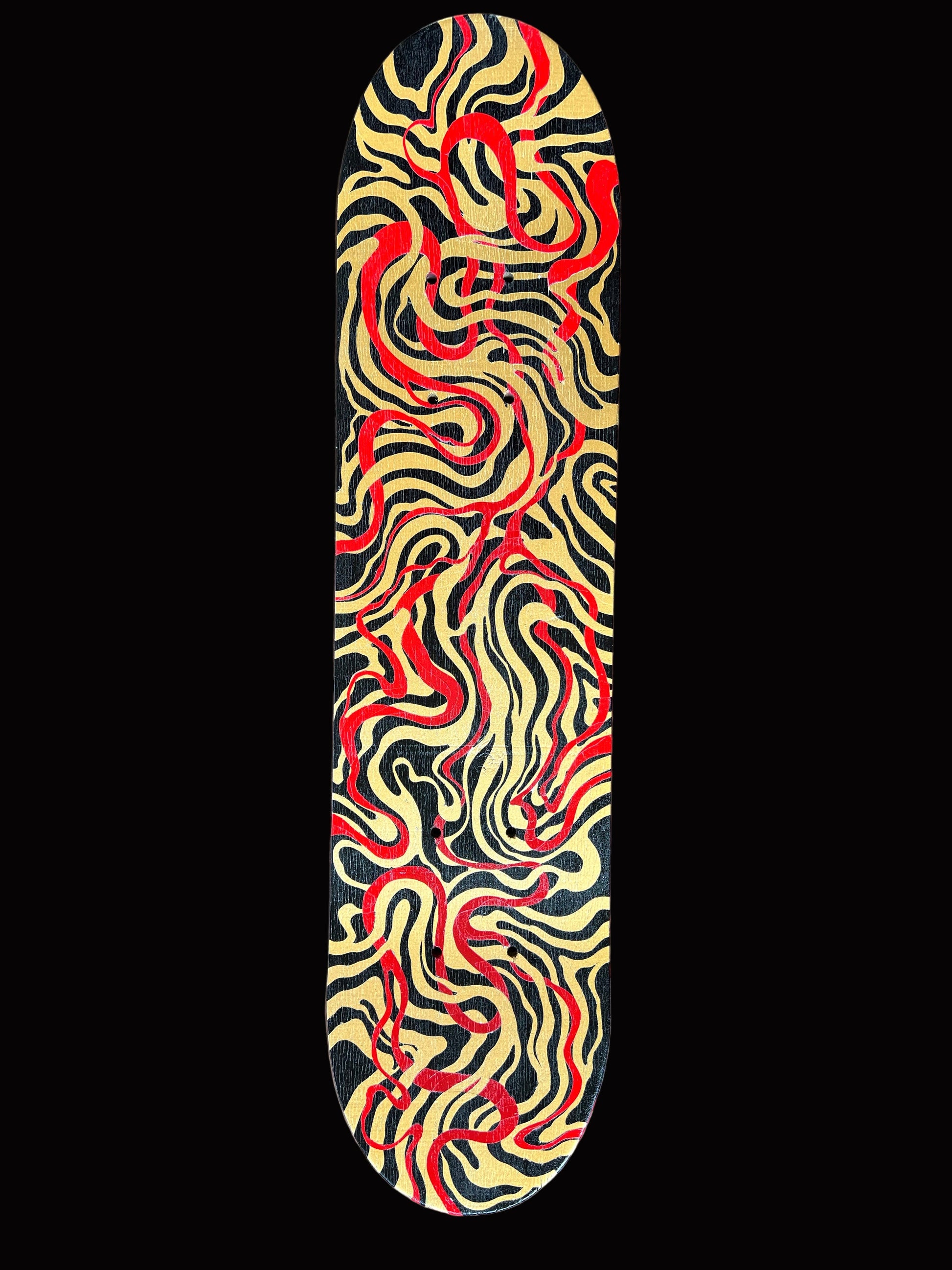 Skateboard deck with red and gold abstract pattern on a wooden surface