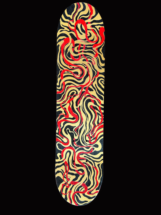 Skateboard deck with red and gold abstract pattern on a wooden surface